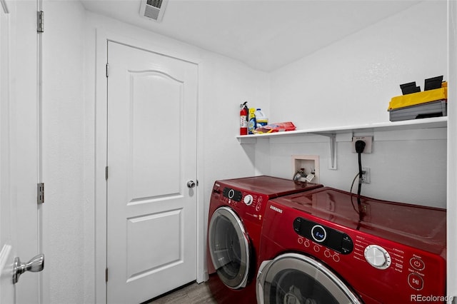 laundry room with laundry area, visible vents, separate washer and dryer, and wood finished floors