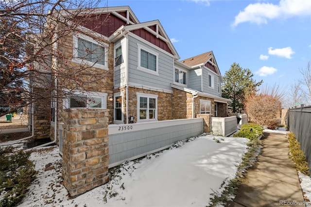 exterior space with stone siding, fence, and board and batten siding