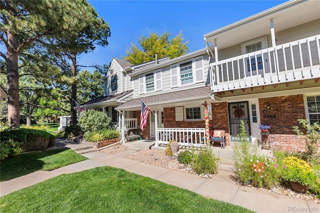 view of front of property with a balcony, a porch, and a front yard