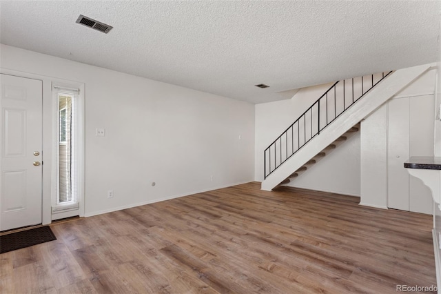 6650 E Arizona Ave Unit 203, Denver, CO 80224 - unfurnished living room featuring wood finished floors, stairway, a textured ceiling, and baseboards