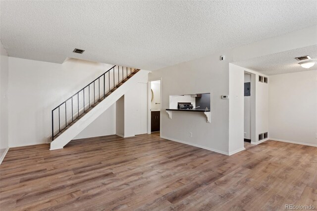 6650 E Arizona Ave Unit 203, Denver, CO 80224 - unfurnished living room with wood finished floors, a textured ceiling, stairway, and baseboards