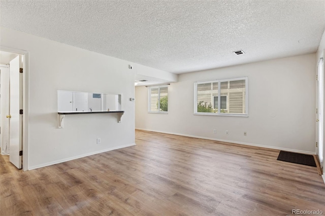 6650 E Arizona Ave Unit 203, Denver, CO 80224 - unfurnished living room featuring a textured ceiling, wood finished floors, and baseboards