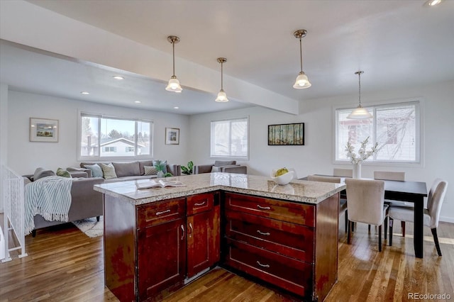 kitchen with dark hardwood / wood-style floors, a center island, hanging light fixtures, and light stone countertops