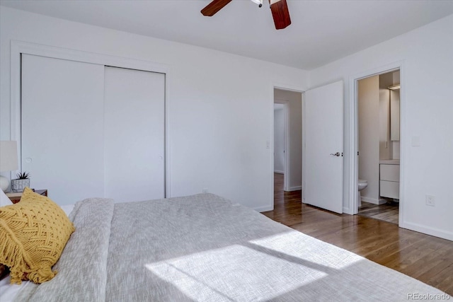 bedroom with dark wood-type flooring, connected bathroom, ceiling fan, and a closet