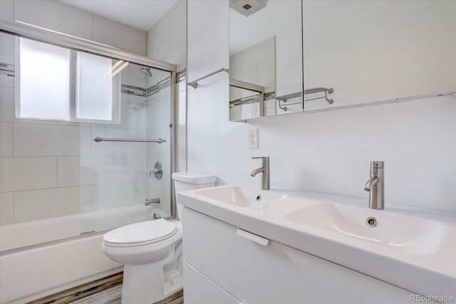 full bathroom with enclosed tub / shower combo, vanity, and toilet