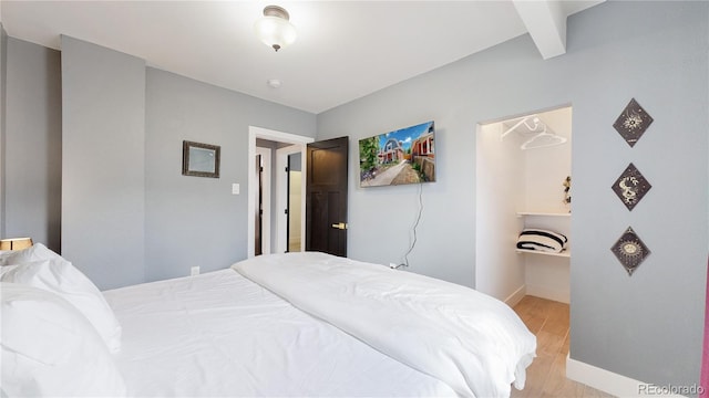 bedroom featuring light hardwood / wood-style floors and beamed ceiling