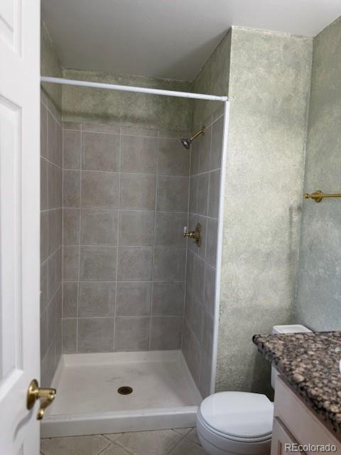 16180 E Flora Pl, Aurora, CO 80013 - bathroom featuring toilet, vanity, tile patterned flooring, and a tile shower