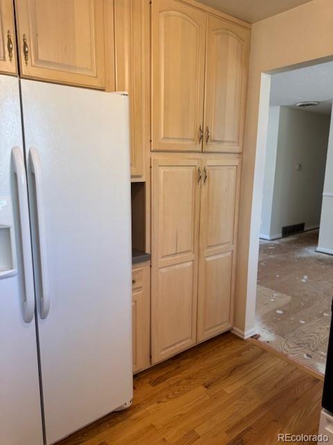 16180 E Flora Pl, Aurora, CO 80013 - kitchen with white refrigerator with ice dispenser, light wood finished floors, light brown cabinetry, and baseboards