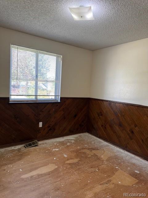 16180 E Flora Pl, Aurora, CO 80013 - spare room featuring wainscoting, wooden walls, and a textured ceiling