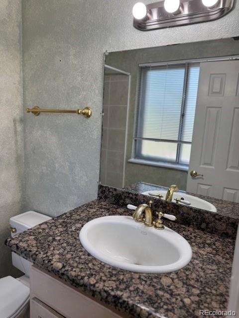16180 E Flora Pl, Aurora, CO 80013 - full bathroom featuring vanity, toilet, a shower, and a textured wall
