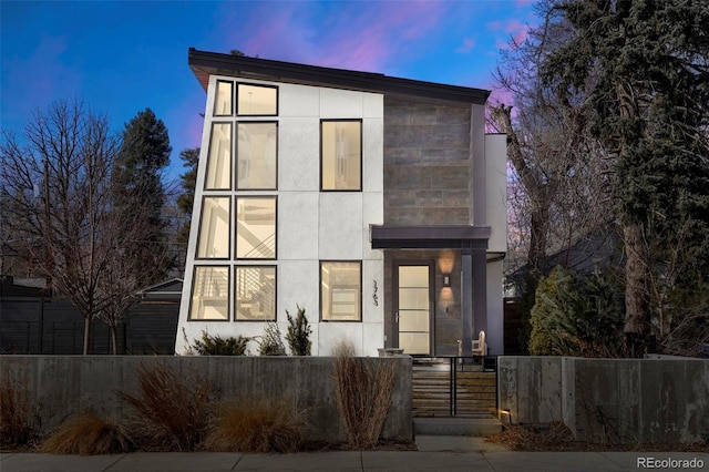 contemporary home featuring a fenced front yard and stucco siding