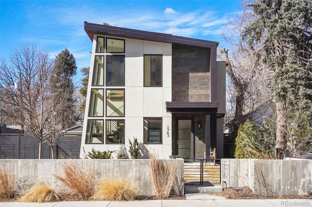 contemporary house featuring stucco siding and a fenced front yard
