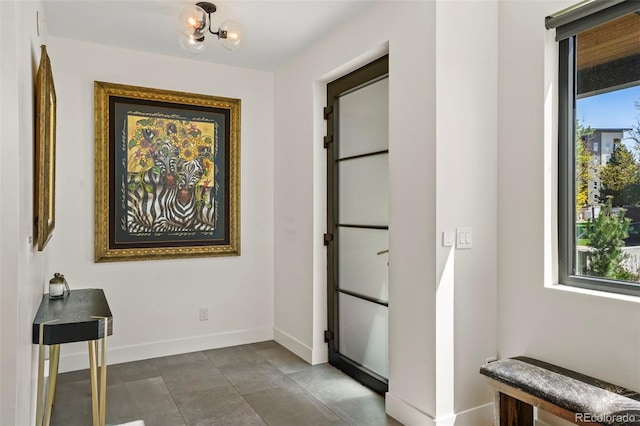 hallway featuring baseboards and a notable chandelier