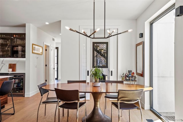 dining room with a notable chandelier, light wood-type flooring, baseboards, recessed lighting, and wine cooler