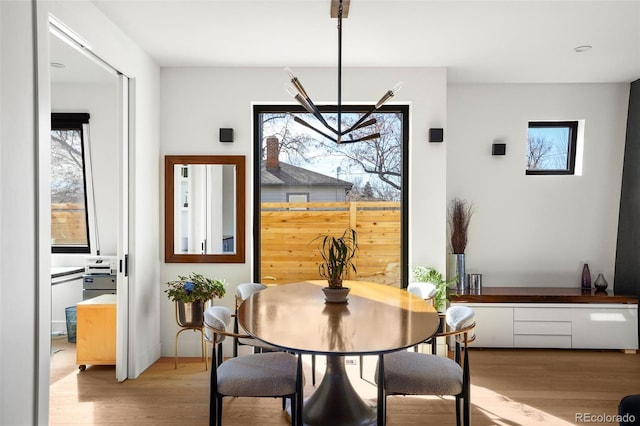 dining area with light wood-style floors and a notable chandelier