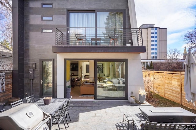 rear view of house with a patio area, stucco siding, fence, and a balcony