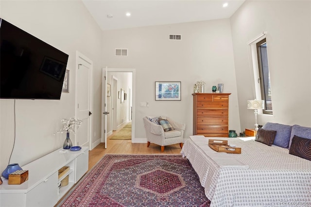 bedroom featuring recessed lighting, light wood finished floors, visible vents, and a high ceiling