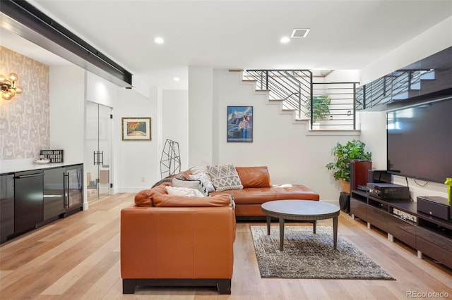 living area with light wood-style floors, baseboards, visible vents, and stairs