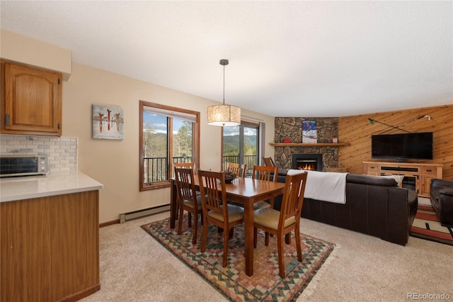 143 Forest Trl Unit 210, Winter Park, CO 80482 - dining area featuring a stone fireplace, light colored carpet, a baseboard heating unit, wood walls, and baseboards