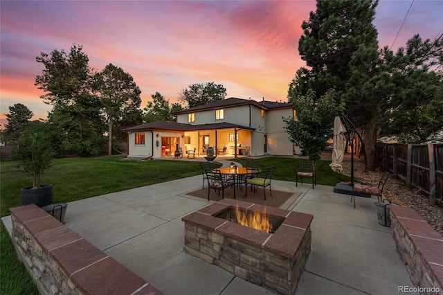 patio terrace at dusk featuring a lawn and an outdoor fire pit