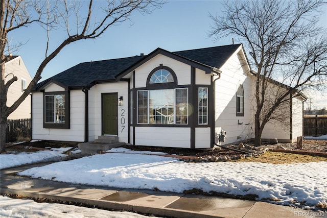 view of front of home featuring entry steps, roof with shingles, and fence