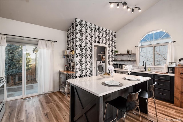 kitchen with lofted ceiling, washer / dryer, sink, and plenty of natural light