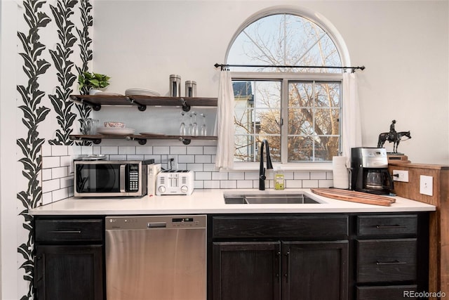 kitchen featuring tasteful backsplash, stainless steel appliances, a sink, and light countertops