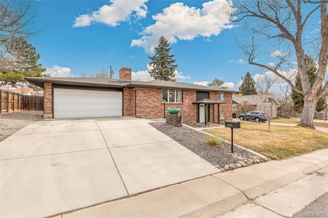 6614 Everett St, Arvada, CO 80004 - view of front of house featuring an attached garage, driveway, a chimney, and brick siding