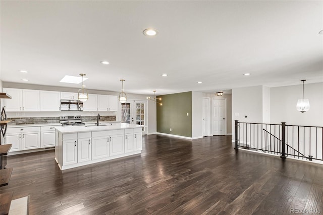6614 Everett St, Arvada, CO 80004 - kitchen featuring appliances with stainless steel finishes, recessed lighting, open floor plan, dark wood finished floors, and an island with sink