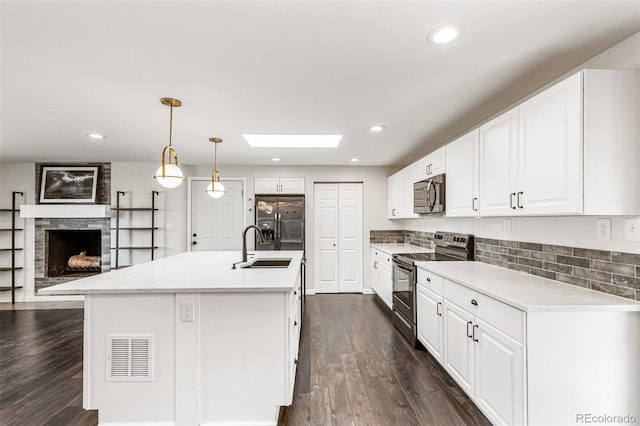 6614 Everett St, Arvada, CO 80004 - kitchen with stainless steel appliances, a skylight, dark wood-style floors, white cabinetry, and recessed lighting