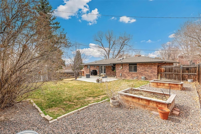 6614 Everett St, Arvada, CO 80004 - rear view of property with a patio area, a fenced backyard, brick siding, a shingled roof, and a garden