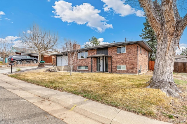 6614 Everett St, Arvada, CO 80004 - split foyer home with brick siding, a garage, a chimney, and driveway