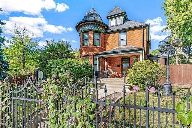 view of front of house featuring covered porch, brick siding, a fenced front yard, and a gate