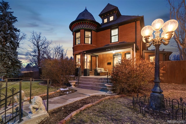 victorian house with brick siding and fence