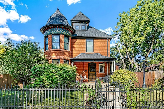 victorian house with brick siding and a fenced front yard