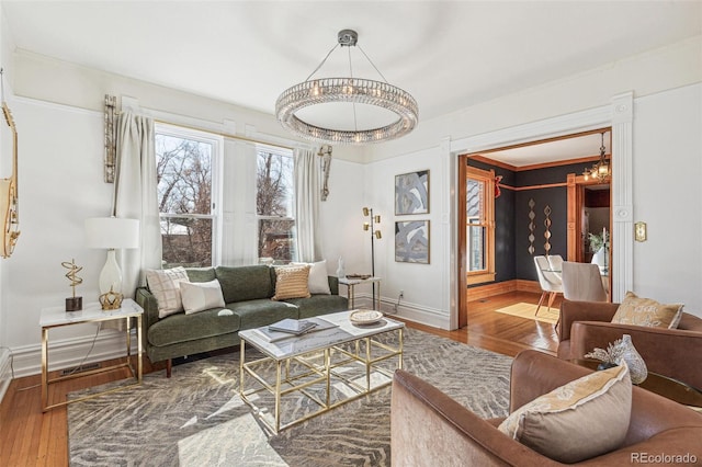 living area with an inviting chandelier, baseboards, and wood finished floors