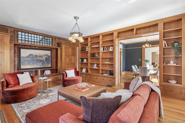 living room featuring a chandelier, built in shelves, and wood finished floors