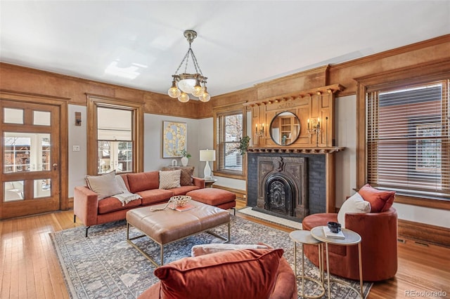 living room featuring a notable chandelier, a fireplace, a wealth of natural light, and light wood-style floors