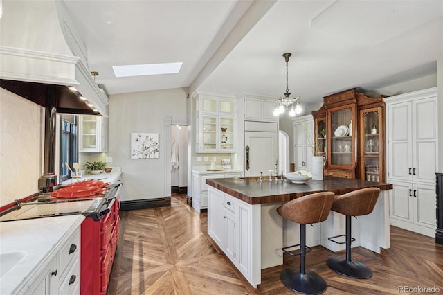 kitchen with premium appliances, white cabinets, glass insert cabinets, and a kitchen breakfast bar