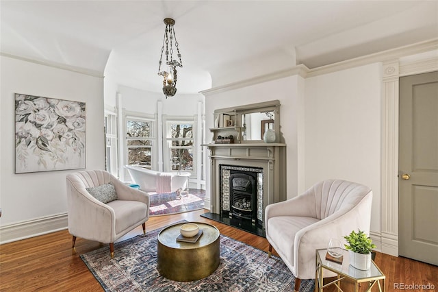 living area featuring ornamental molding, a fireplace with raised hearth, and wood finished floors