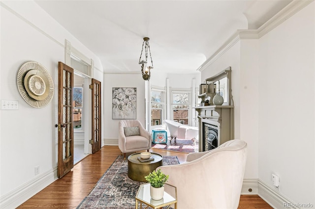 sitting room featuring ornamental molding, a fireplace, wood finished floors, and baseboards