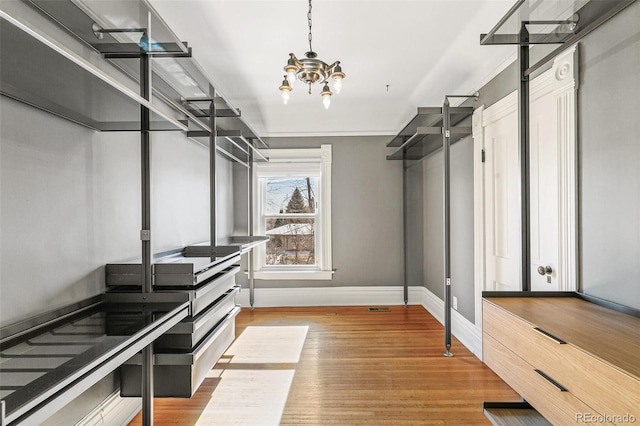 walk in closet featuring a chandelier and wood finished floors