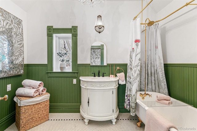 bathroom with a wainscoted wall, a freestanding bath, a shower with shower curtain, and vanity