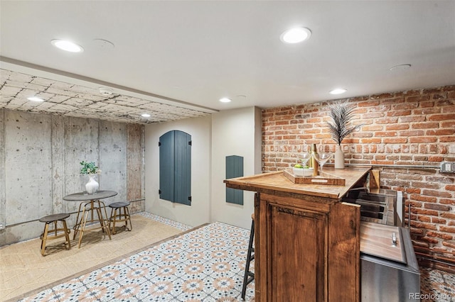 bar with light floors, brick wall, bar, and recessed lighting