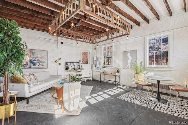 living area featuring concrete flooring, beam ceiling, a towering ceiling, and brick wall