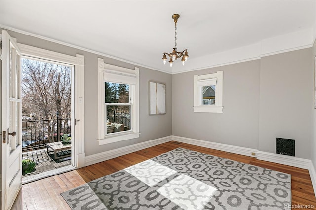 interior space with baseboards, visible vents, hardwood / wood-style floors, and an inviting chandelier