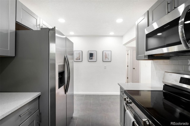 1180 Newark St, Aurora, CO 80010 - kitchen featuring appliances with stainless steel finishes, baseboards, tasteful backsplash, gray cabinetry, and recessed lighting