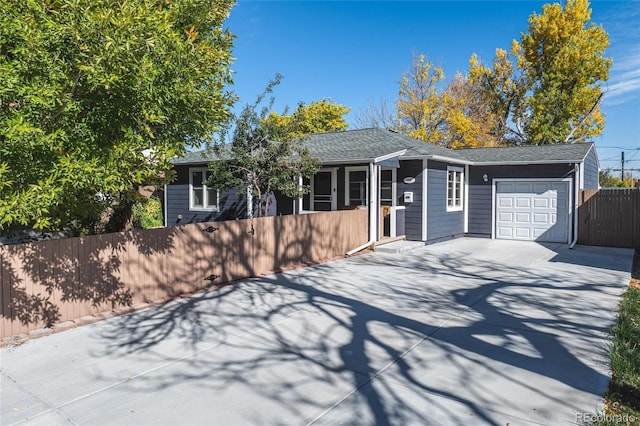 ranch-style house featuring driveway, a fenced front yard, and a garage