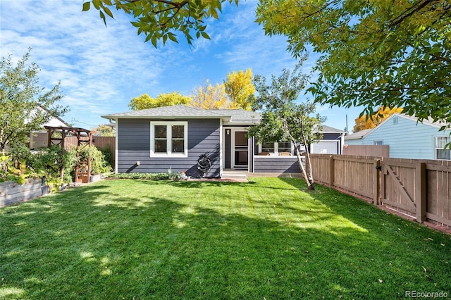 rear view of property featuring a fenced backyard, a gate, and a yard