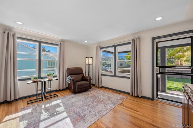 living area with baseboards, wood finished floors, a wealth of natural light, and recessed lighting